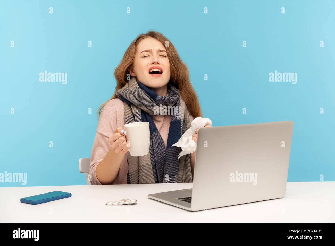 Krankes Mädchen, das sich am Schreibtisch mit Laptop aufhält und hart niest, hustet, kranke freiberufliche Frau mit kalter Arbeit vom Heimbüro, behandelt Stockfoto