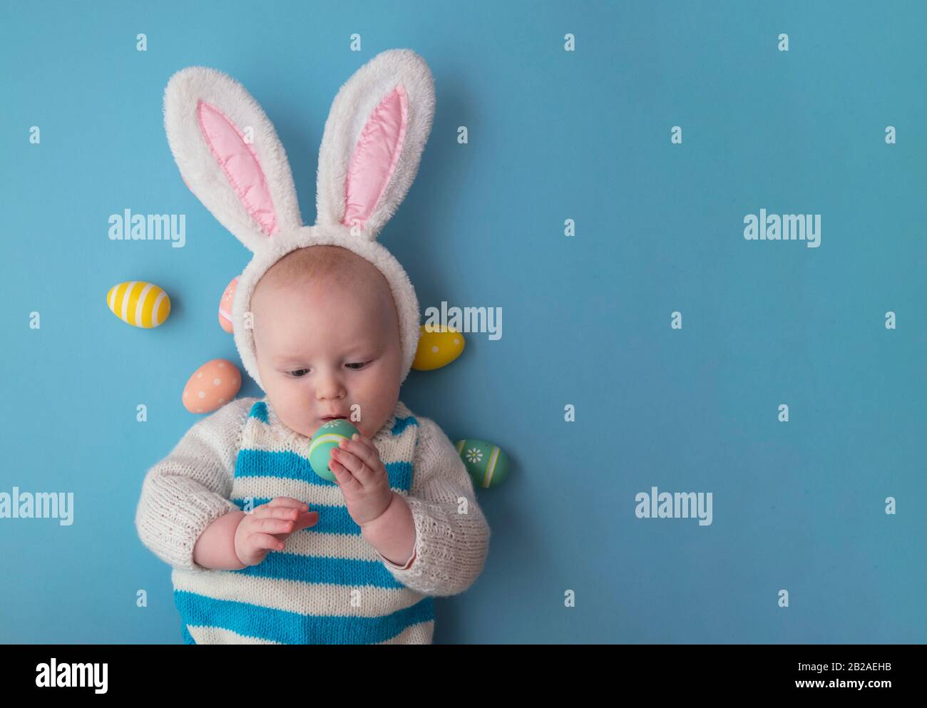 Süßes Baby mit osterbüschen, umgeben von ostereiern. Stockfoto