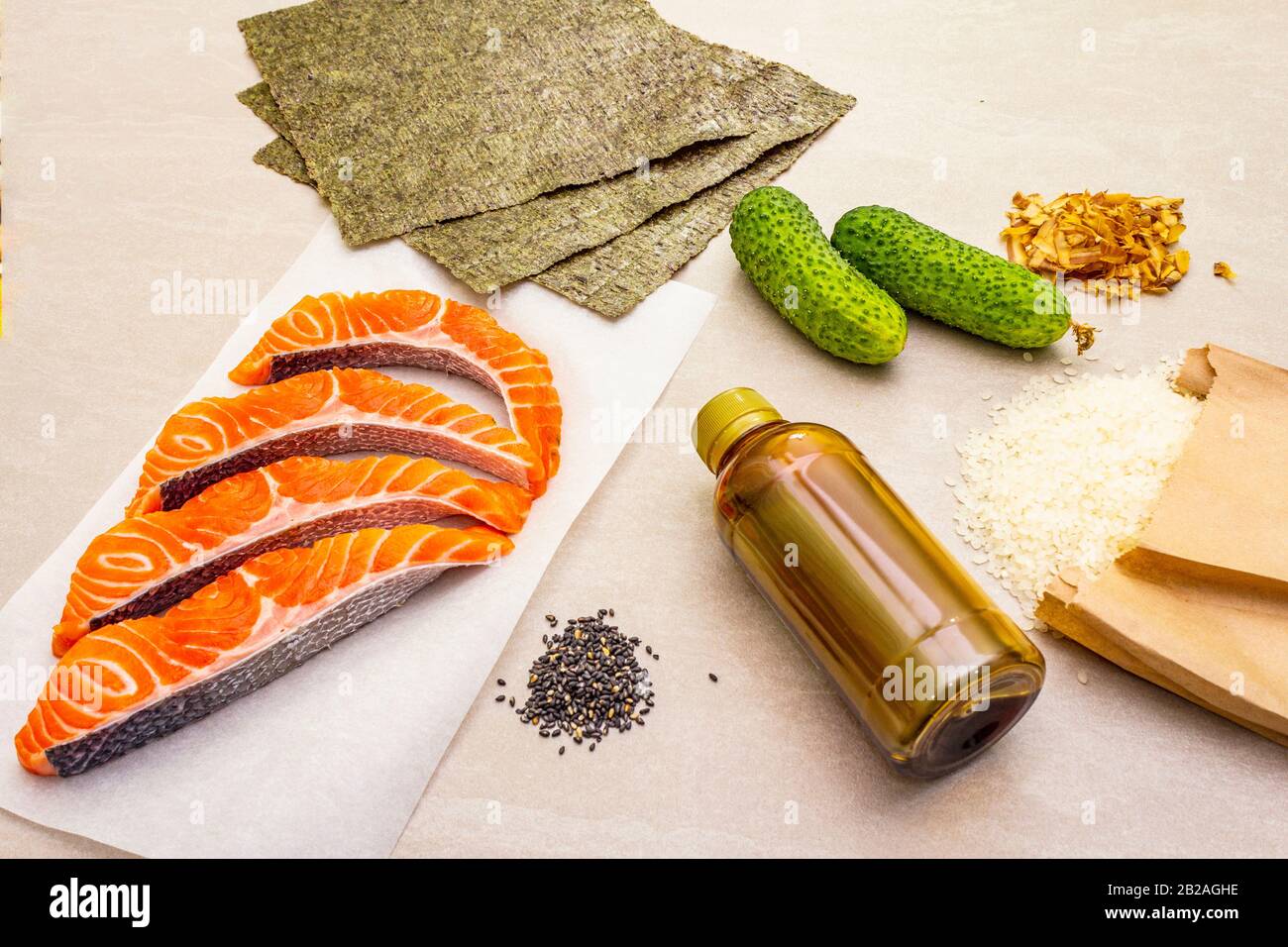 Satz traditioneller Zutaten für japanische Brötchen. Forelle (Lachs), Nori, Gurke, Reis, Bonito Thunfisch Flocken, Sojasoße, Sesamsamen. Die Konce Stockfoto