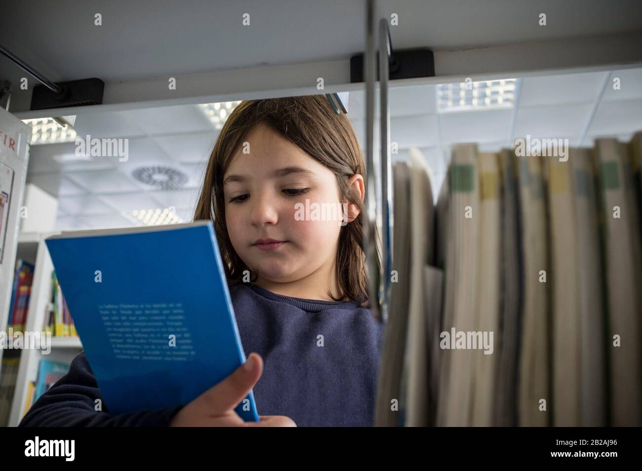 Junge Mädchen Auswahl der Bücher aus der Bibliothek Bücherregal. Kinder Kreativität und Phantasie Konzept. Stockfoto