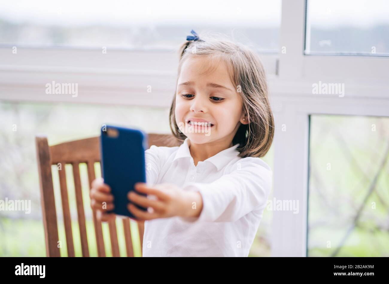 Ein kleines Mädchen nimmt mit dem Handy zuhause ein Foto auf Stockfoto