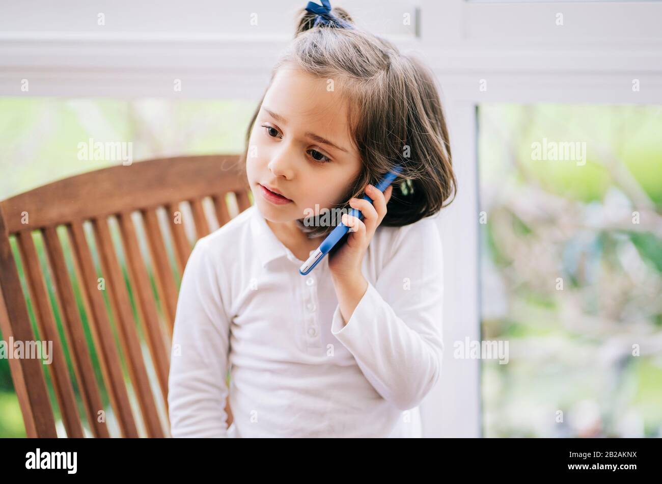 Ein kleines Mädchen ruft zu Hause mit dem Handy an Stockfoto