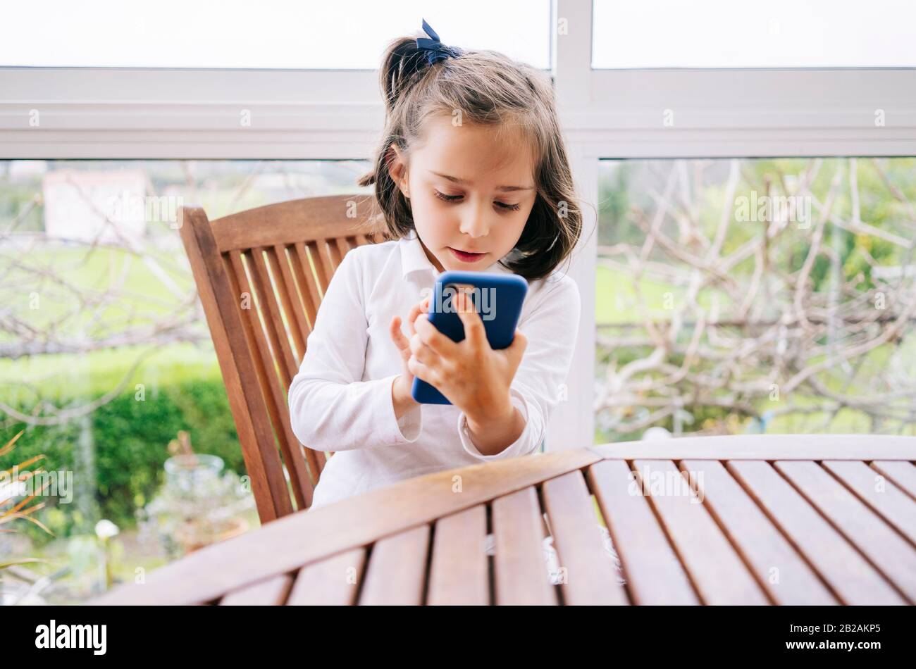 Ein kleines Mädchen benutzt zu Hause ein Handy-Smartphone Stockfoto