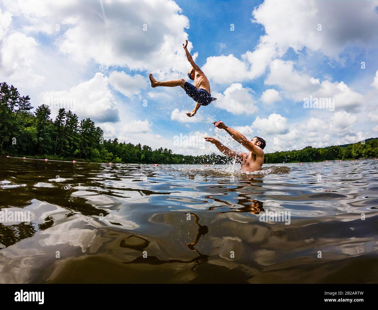 Vater steht in einem See und wirft seinen Sohn in die Luft, USA Stockfoto