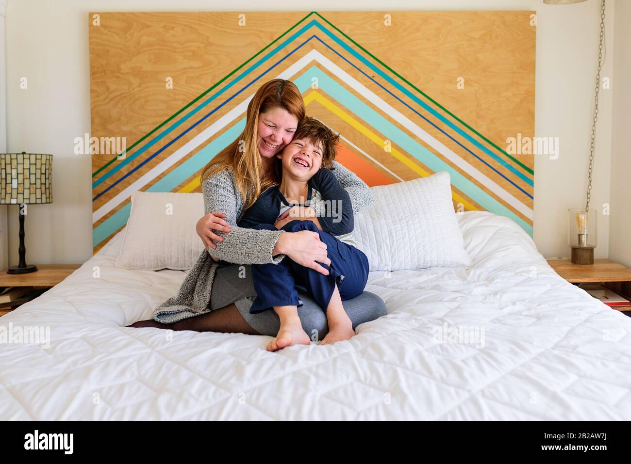 Mutter und Sohn sitzen auf einem Bett und kuscheln Stockfoto