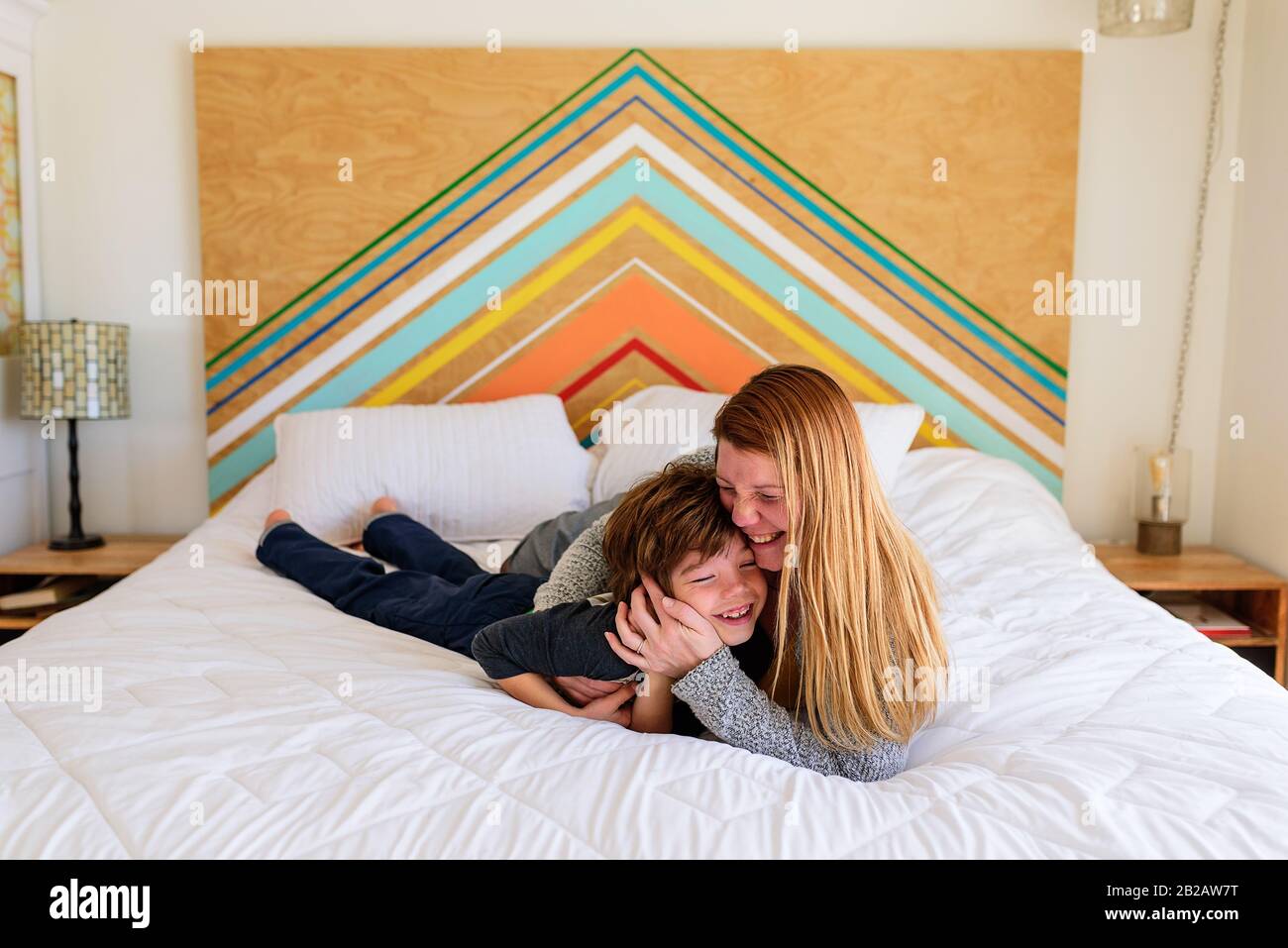 Glückliche Mutter und Sohn, die auf einem Bett liegen, kuscheln Stockfoto