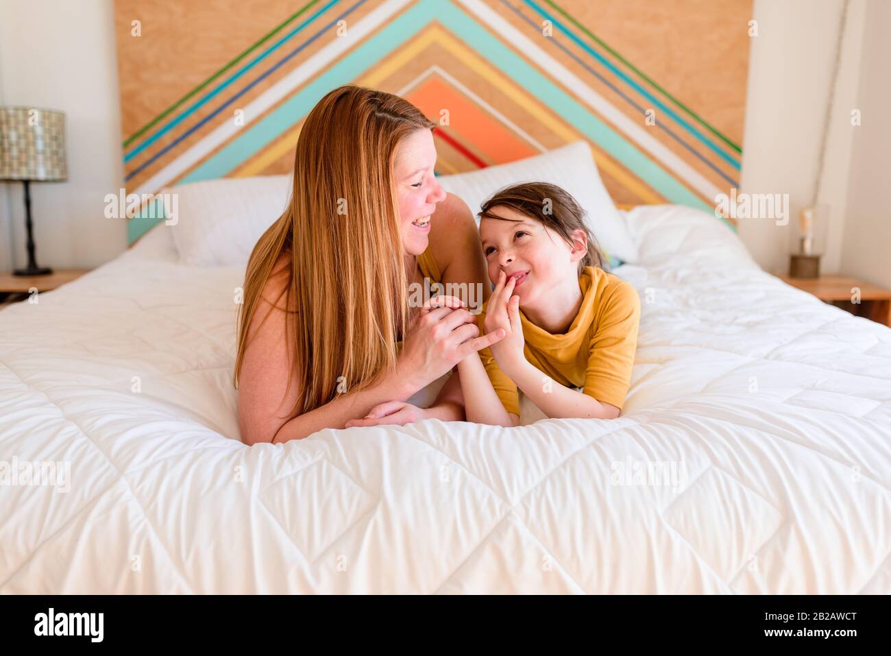 Porträt einer Mutter und Tochter, die auf einem Bett liegen und reden Stockfoto