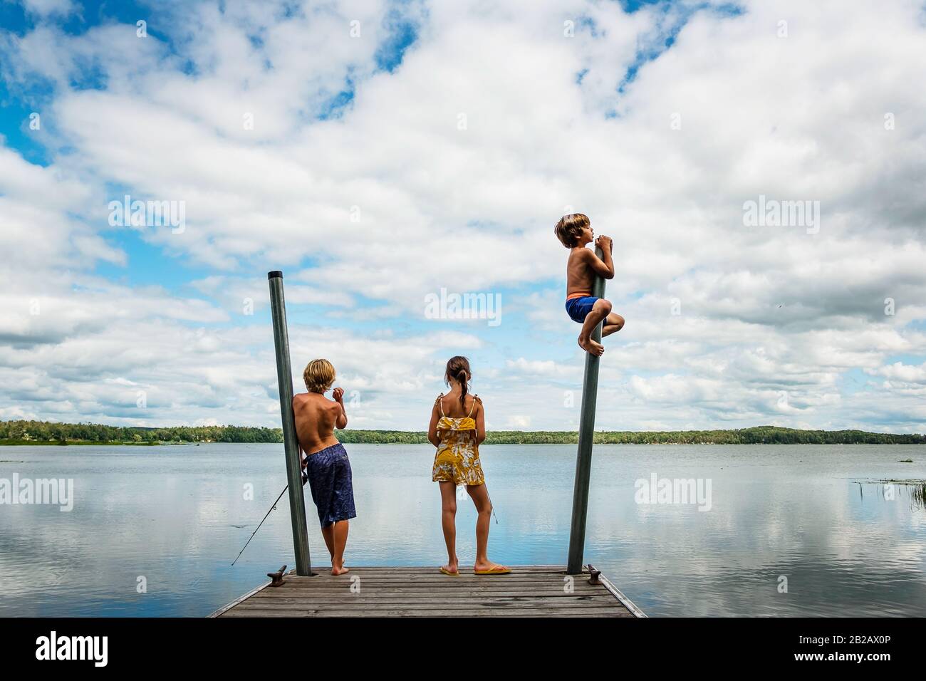 Drei Kinder, die auf einem Dock stehen und dabei angeln und sich darüber durcheinander bringen, USA Stockfoto