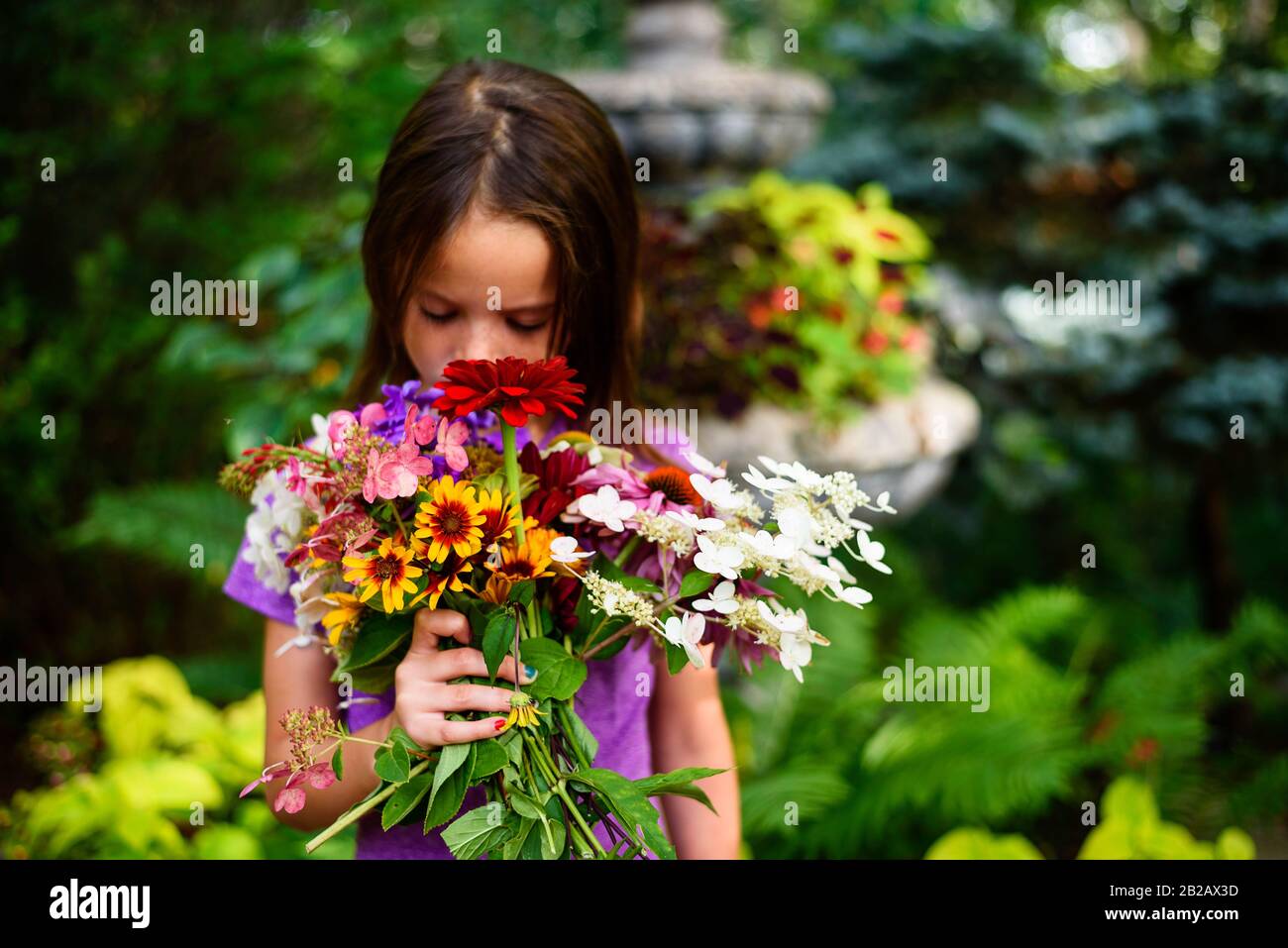 Porträt eines Mädchens, das in einem Garten steht und einen Blumenstrauß riecht, USA Stockfoto