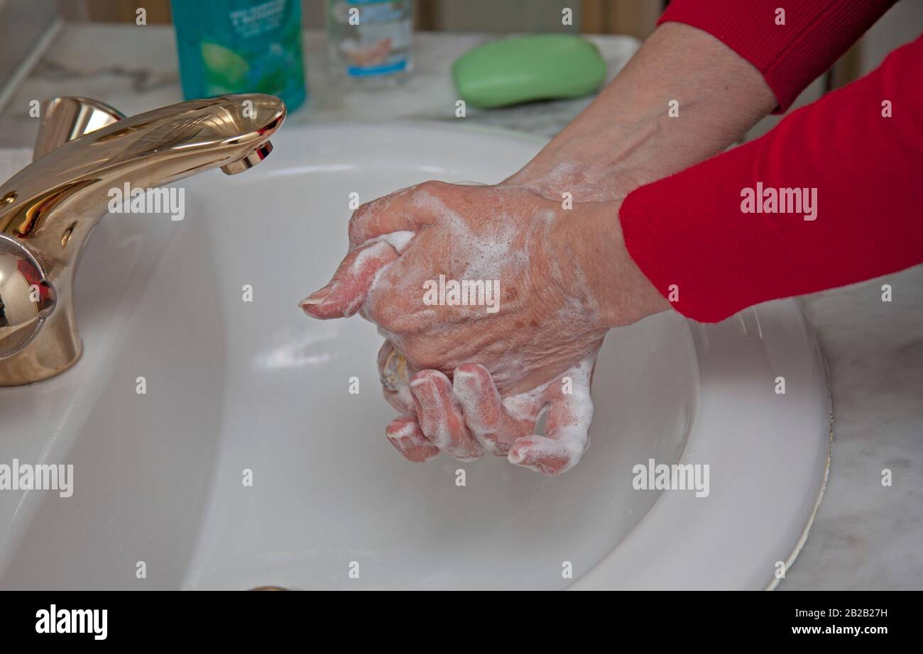 Coronavirus erster Fall in Schottland bestätigt. März 2020. Um das Auffangen und verbreiten des Virus zu verhindern, wird empfohlen, die Hände häufig mit Seife und Wasser zu waschen oder ein Desinfektionsgel zu verwenden. Abbildung: Ältere Frau, die die Hände im Waschbecken im Duschraum waschen. Stockfoto