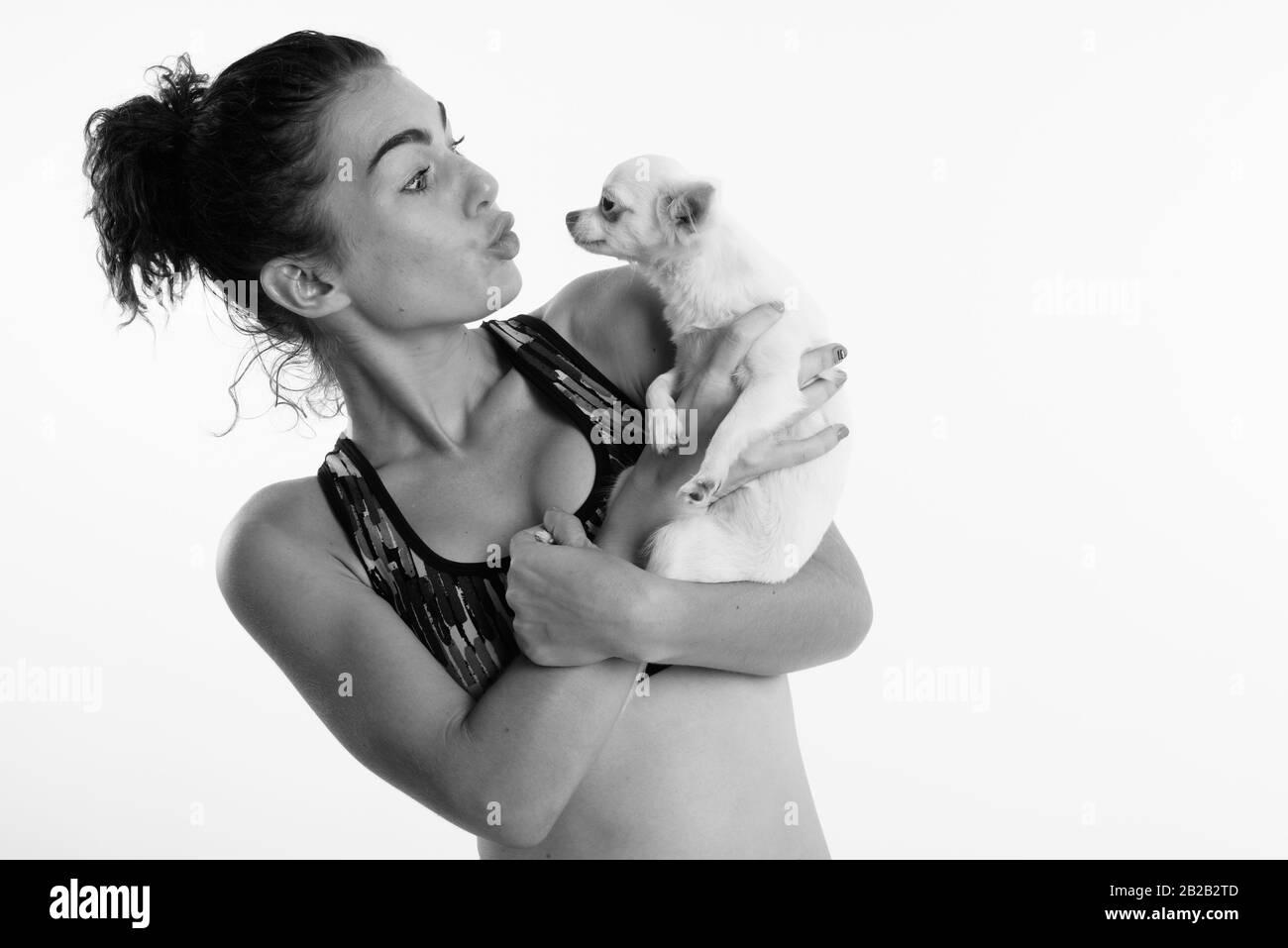 Studio schoss der schönen Teenager halten und küssen niedlichen Hund für Sport und Bewegung gegen den weißen Hintergrund bereit Stockfoto