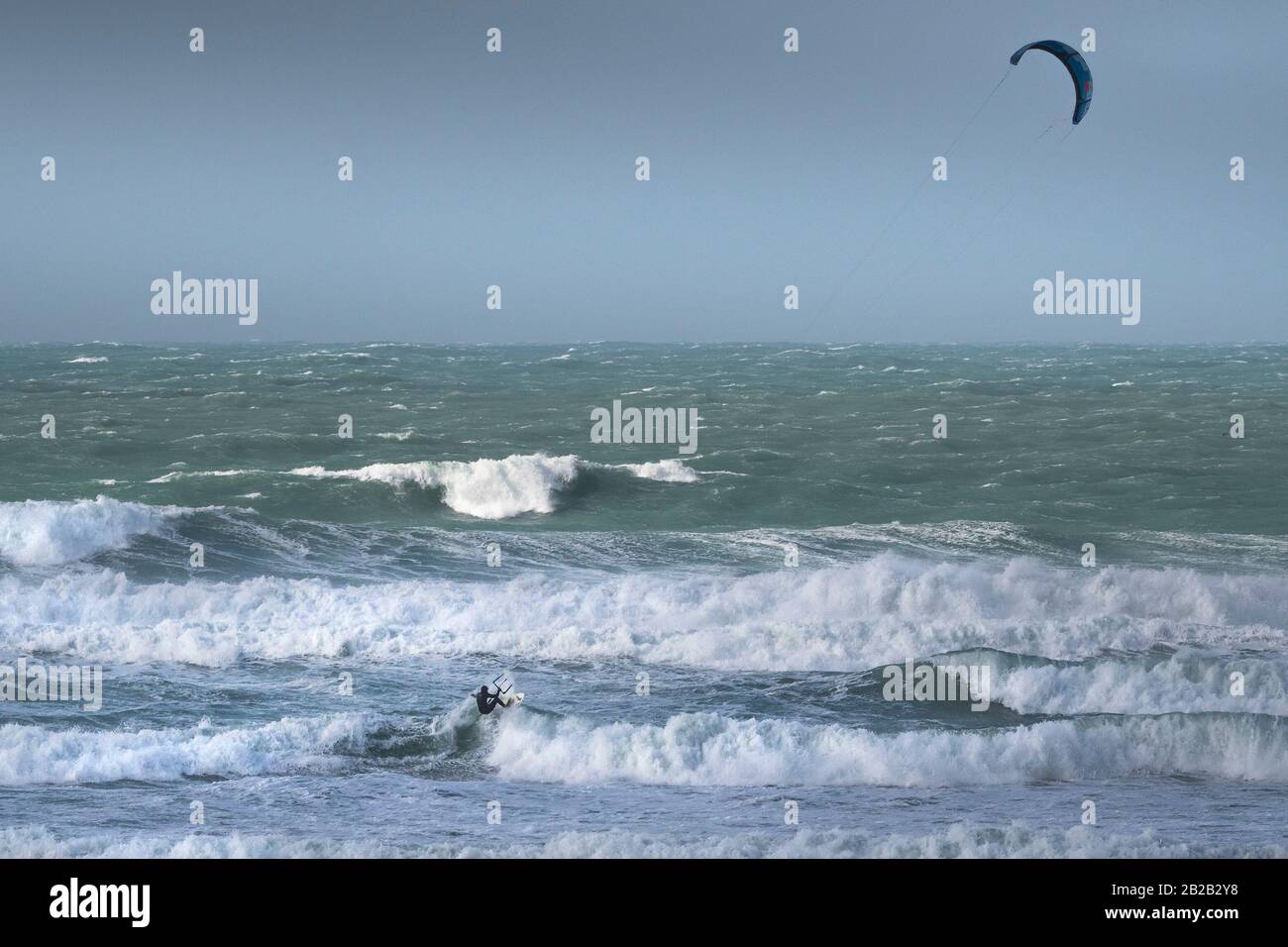 Ein einsamer Kitesurfer, der den starken Wind von Storm Jorge in Fistral in Newquay in Cornwall genießt. Stockfoto