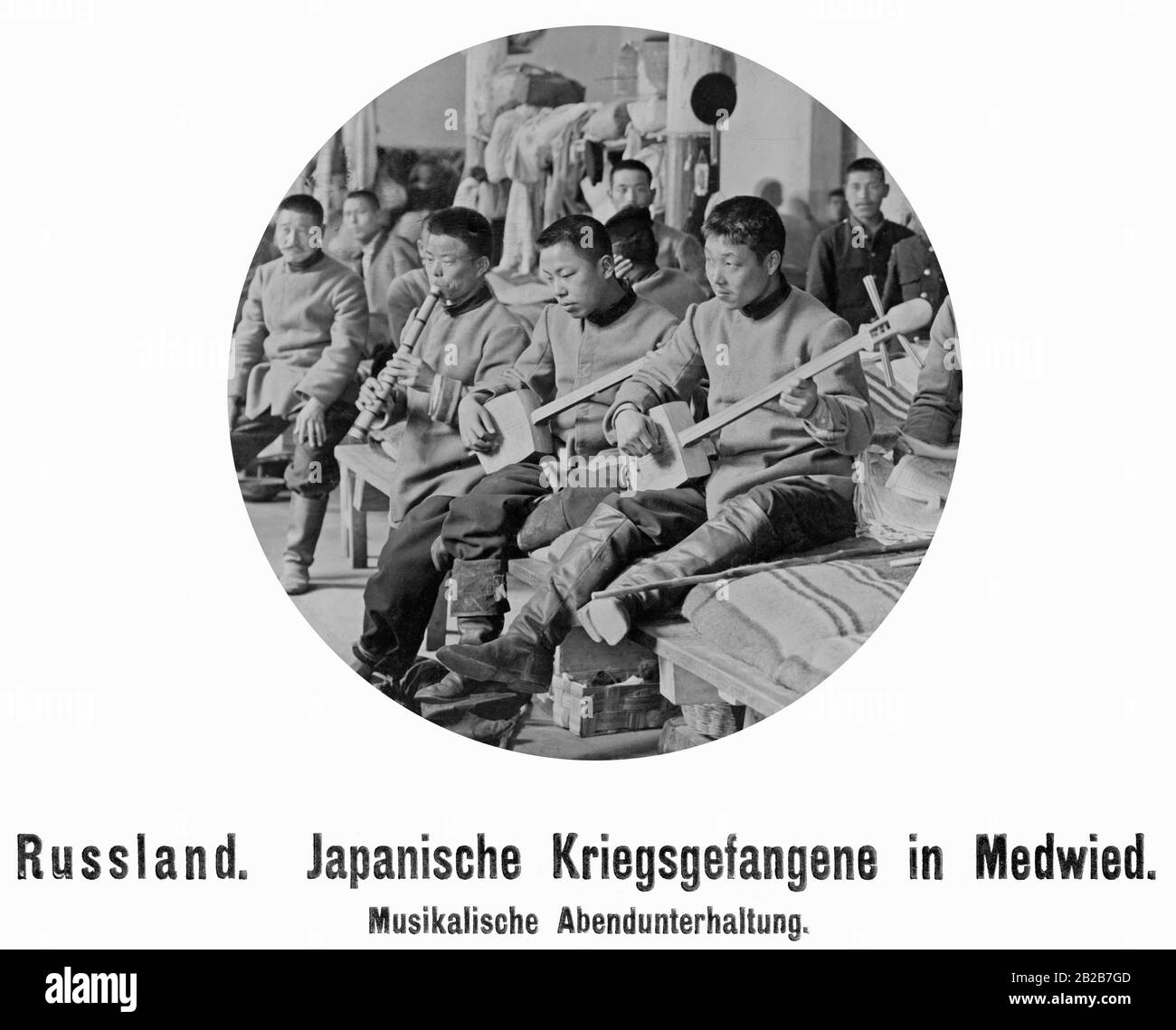 Drei japanische Gefangene spielen Musik, andere hören. Stockfoto