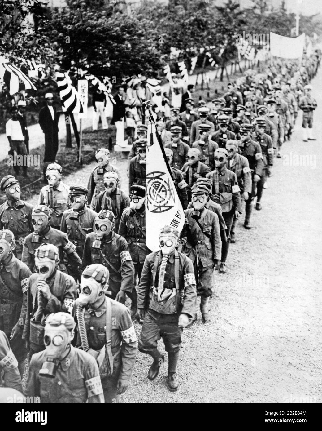 Eine Truppe japanischer Soldaten marschiert im Rahmen einer Demonstration eines luftangriffs in Osaka, Japan, auf einer Straße. Sie tragen Gasmasken. Stockfoto