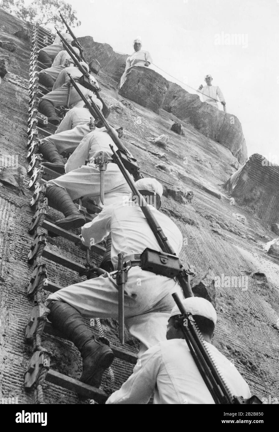 Japanische Soldaten benutzen eine Seilleiter, um im Rahmen einer Übung eine Wand hochzuklettern. Stockfoto