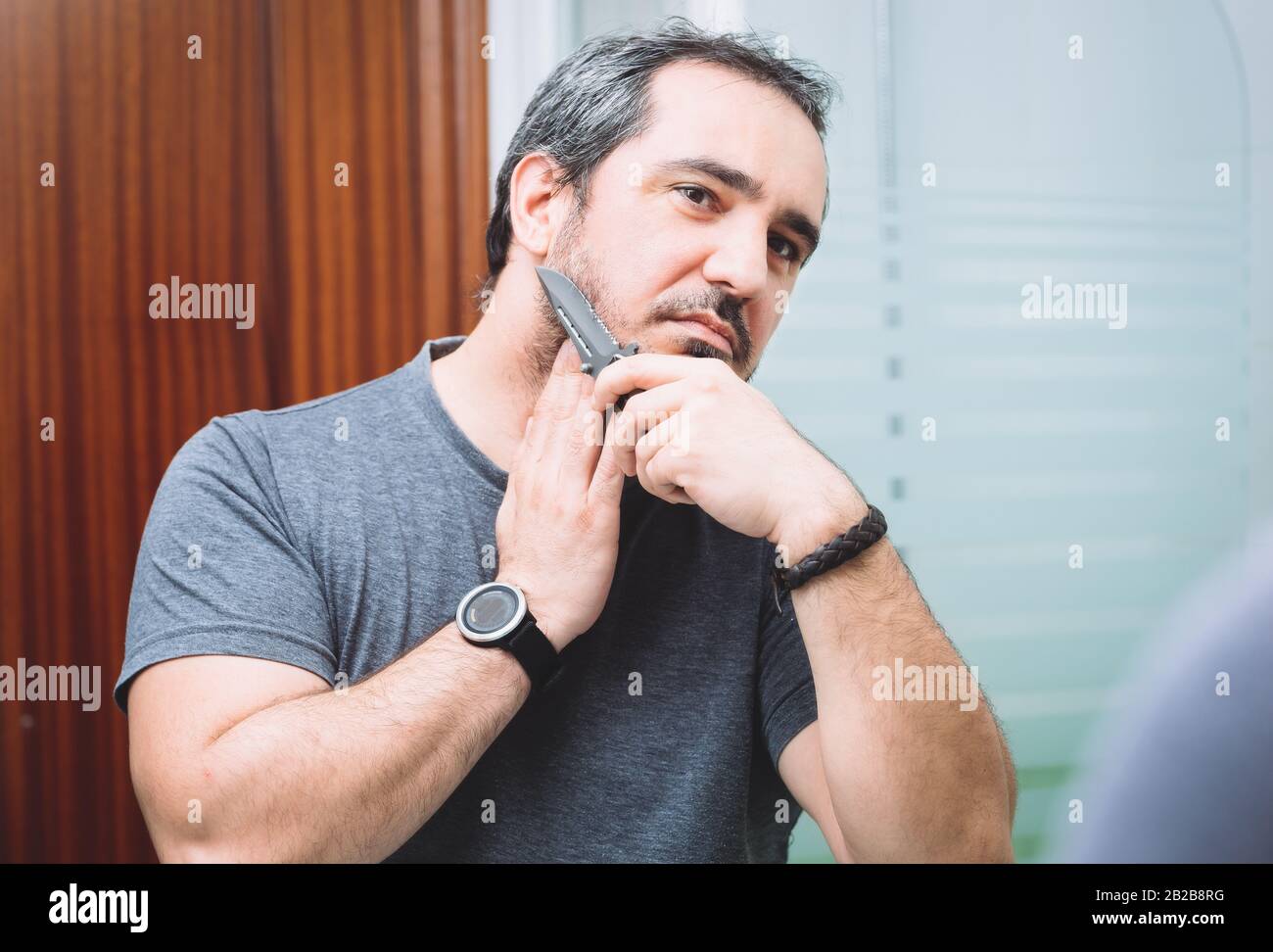 40-er Mann rasieren mit scharfem Jagdmesser Stockfoto