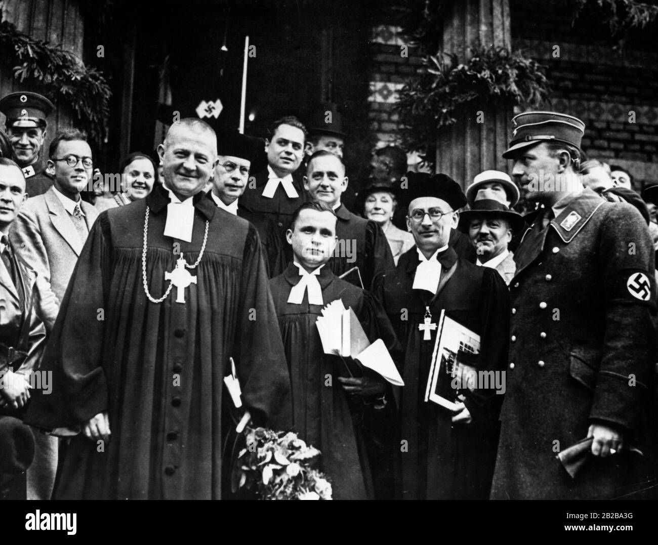 Reichsaußenminister Ludwig Mueller zum 90-jährigen Jubiläum der Erlöserkirche in Sacrow, die mit der Weihe der Heldengedenkschrift und der Bischofsglocke verbunden war. Nach der Zeremonie steht er vor der Kirche. An seinen rechten Pfarrer Schmidt, Probst Loerzer und Graf Helldorf, den Polizeichef von Berlin. Stockfoto