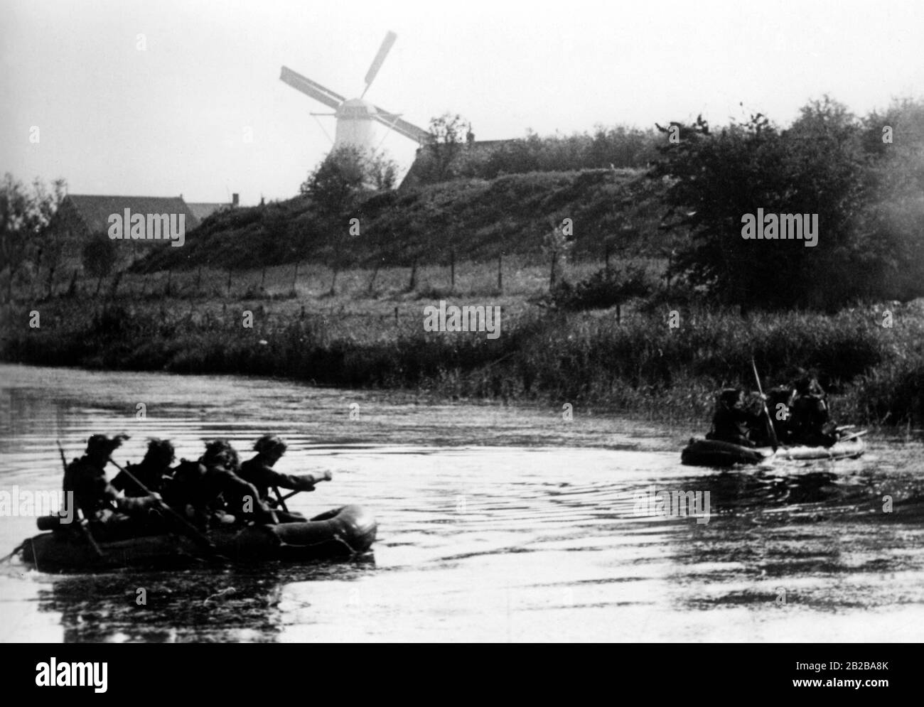 Einmarsch in Holland 1940: Bild zeigt Gummiboote mit deutschen Soldaten beim Angriff der Insel Walcheren und im Rücken eine Windmühle Stockfoto