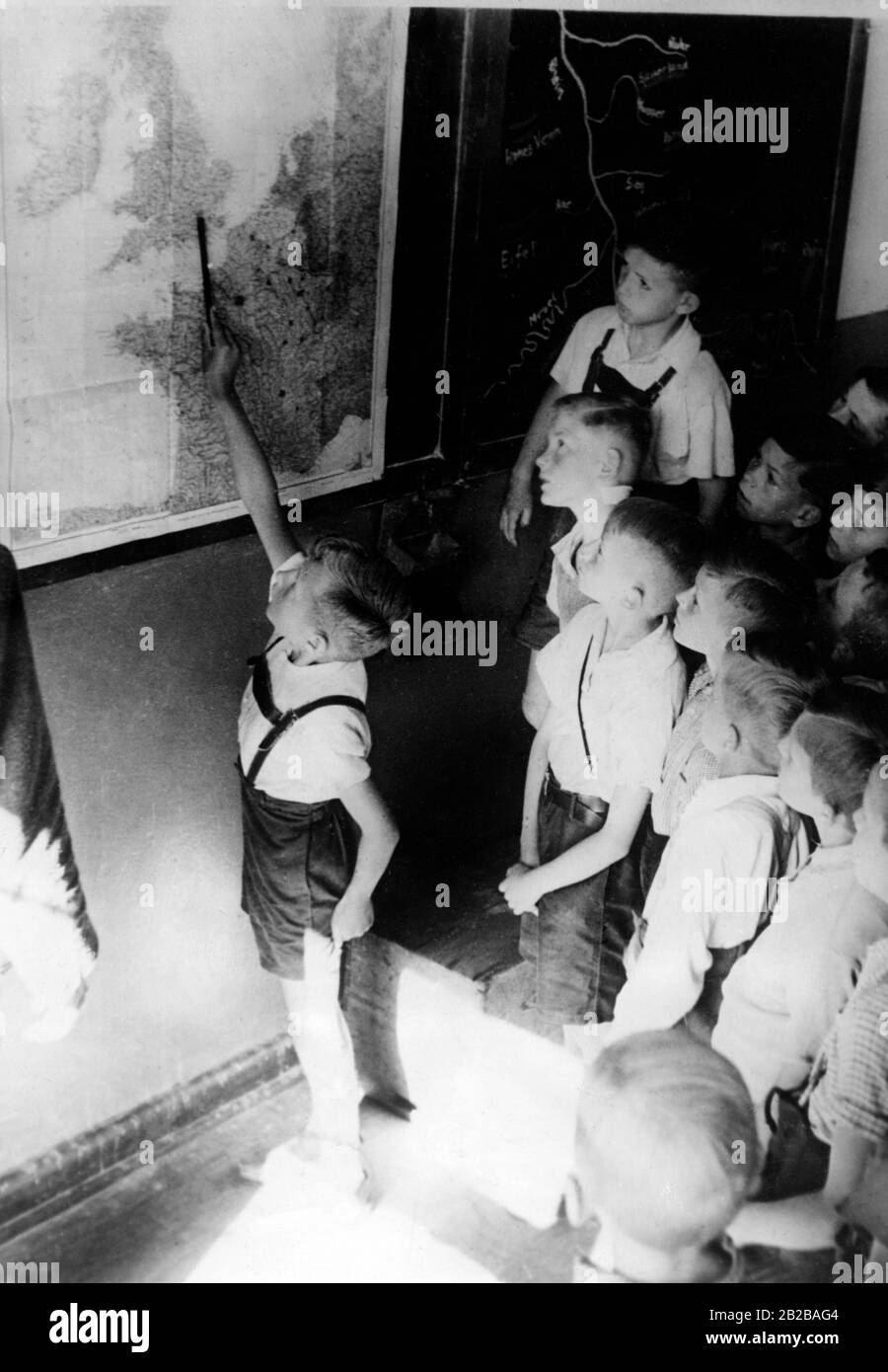 Schuljunge vor einem Kartenweg den Bericht der Wehrmacht. Stockfoto