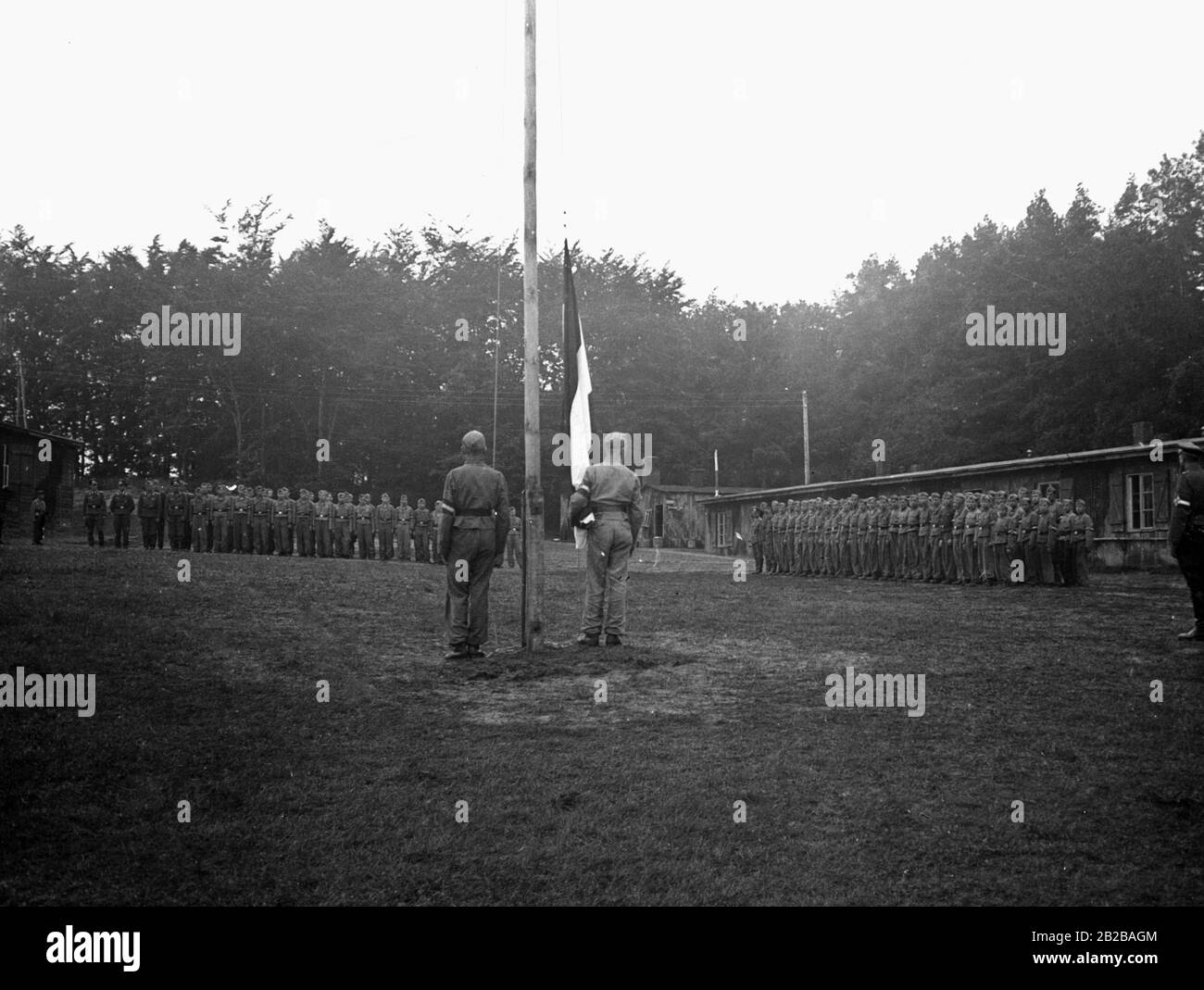 Hitlerjugend, die in einem Truppenübungsplatz eine Fahne hochhisst. Stockfoto