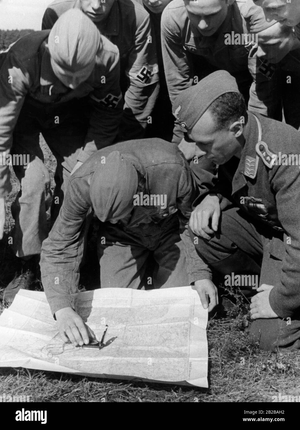Hitler-Jugend-Mitglieder lernen in einem Truppenübungsplatz, wie sie mit einer Karte und einem Kompass ihren Weg finden. Stockfoto