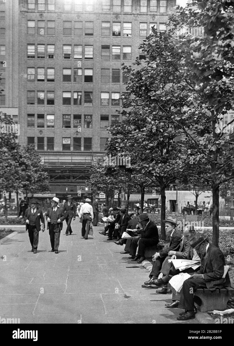 Weltwirtschaftskrise: Arbeitslose sitzen in einem Park in New York und lesen die Zeitung Stockfoto