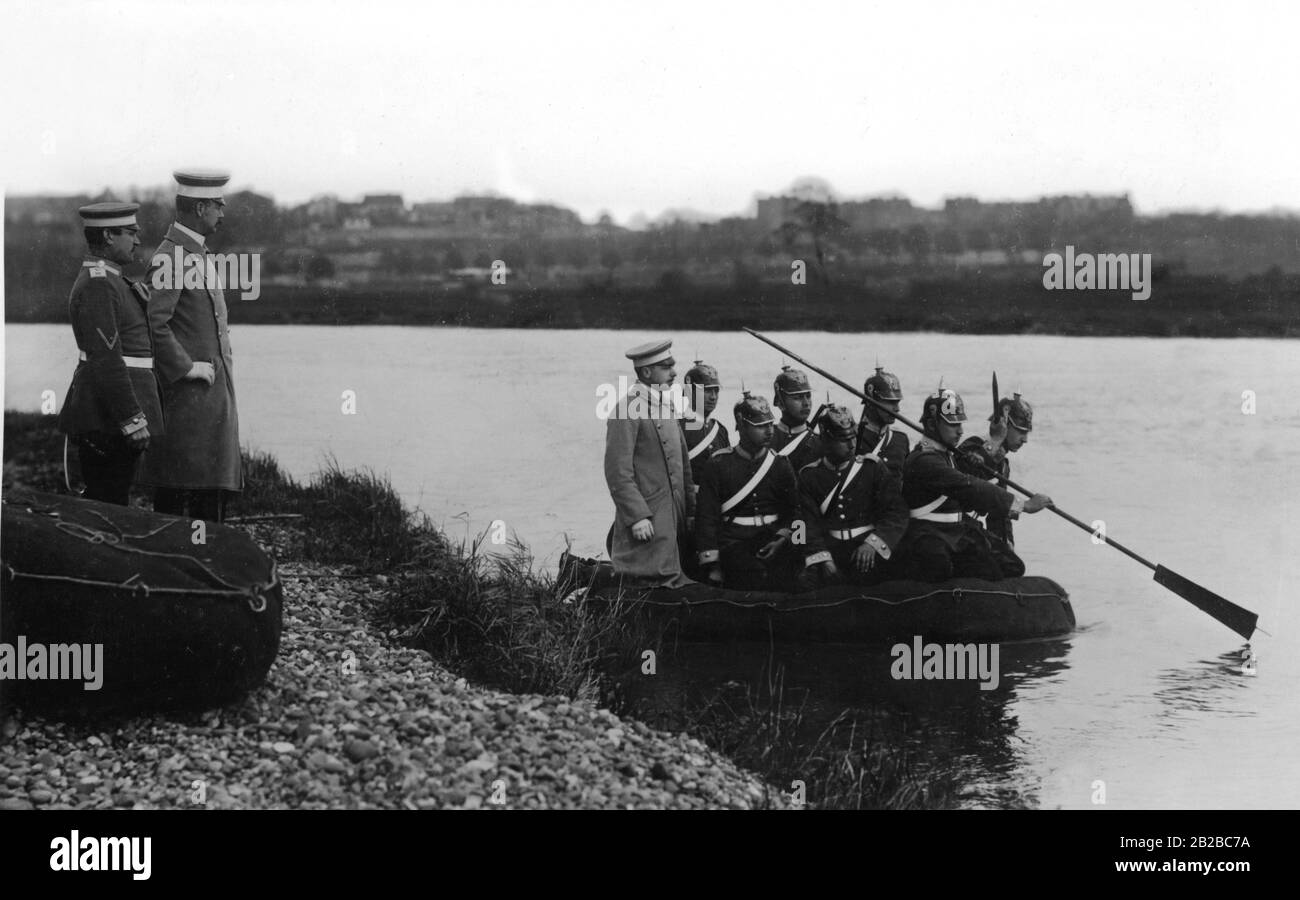 Acht Kavalleristen durchqueren in einem Floßsack einen Wasserkörper. Zwei weitere Beamte beobachten die Übung. Stockfoto
