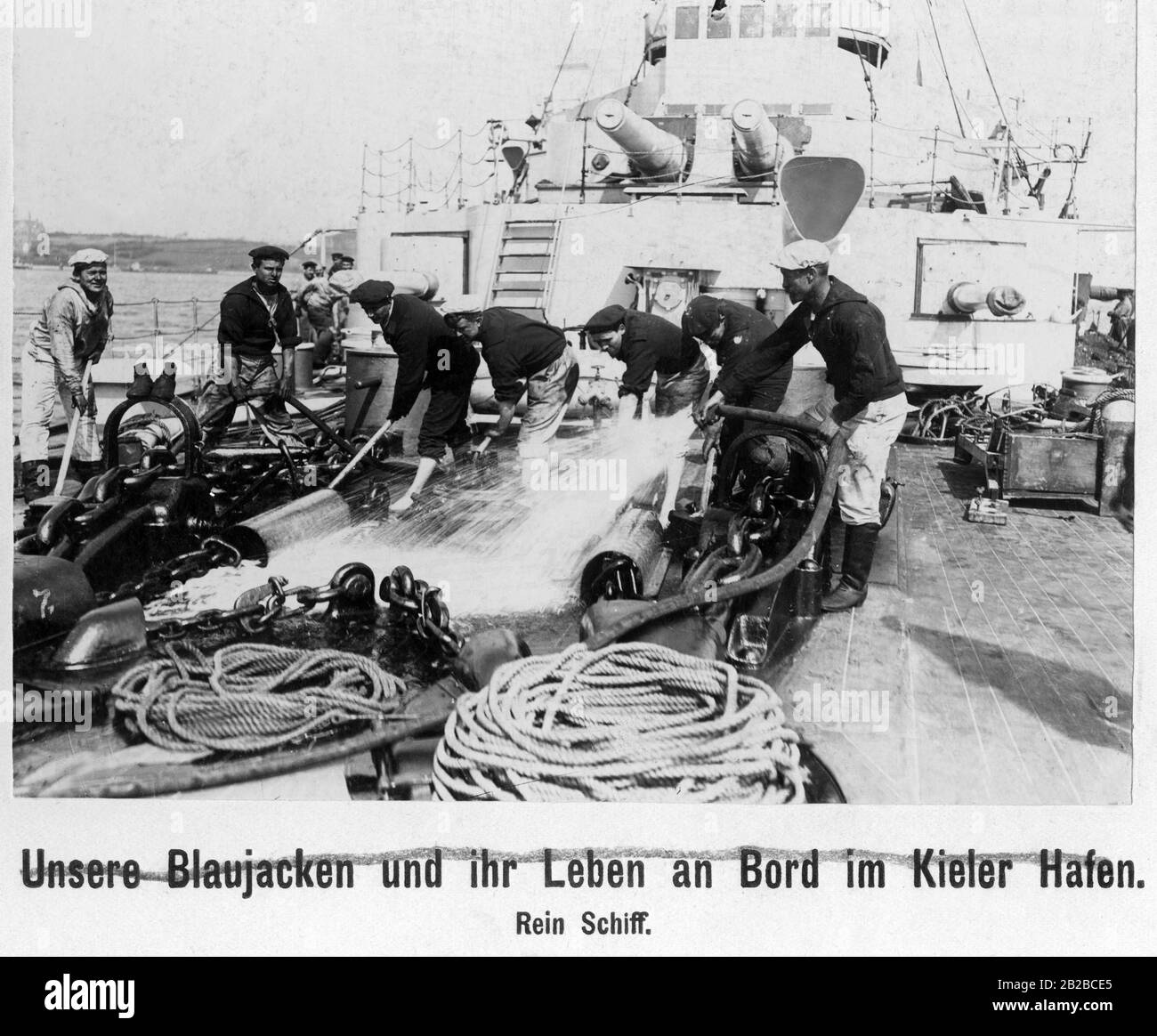 Auf einem deutschen Kriegsschiff säubern einige Matrosen das Vordeck. Stockfoto