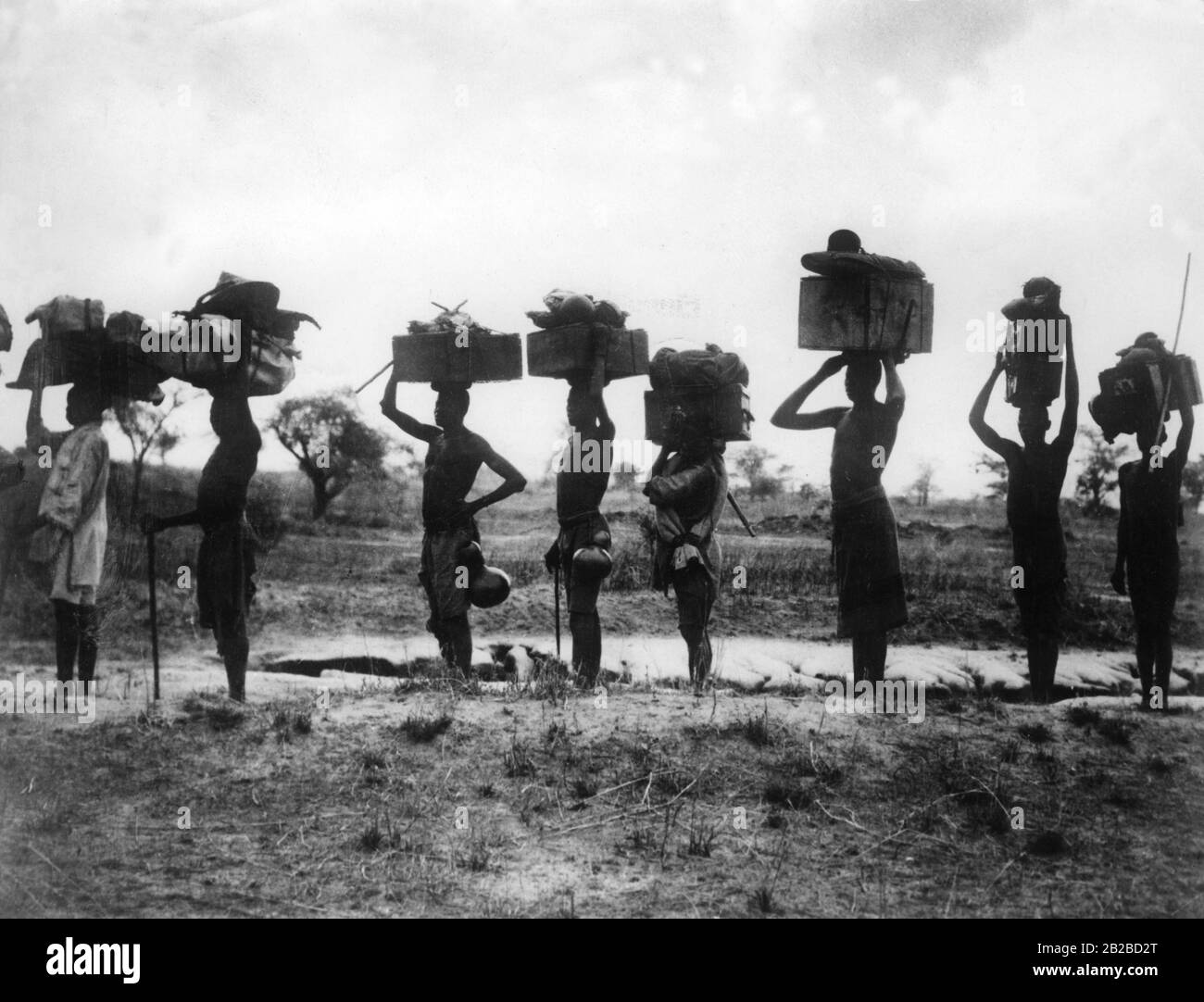 Eine Trägersäule einheimischer Männer im deutschen Ostafrika, im heutigen Uganda, auf dem Weg vom Ende der Straße zum Victoriasee. Vermutlich ein Moviestull, undatiert. Stockfoto