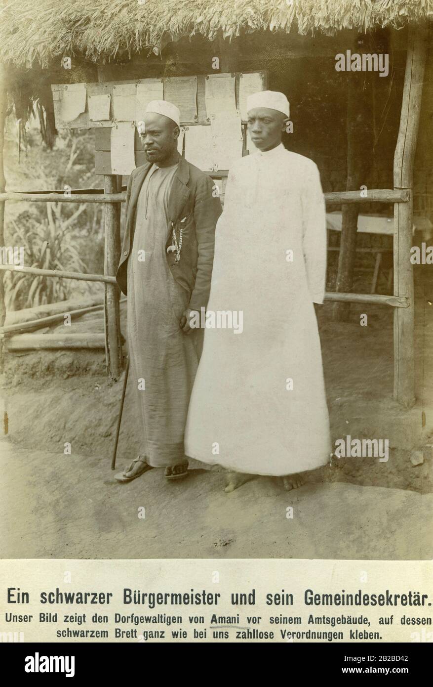Ein Bürgermeister und sein Sekretär vor seinem Bürogebäude im deutschen Ostafrika im heutigen Nordosten Tansanias. Beide tragen omanische arabische Kleidung. Die arabische Minderheit war zu dieser Zeit die Oberschicht über die schwarzafrikanische Bevölkerung. Stockfoto