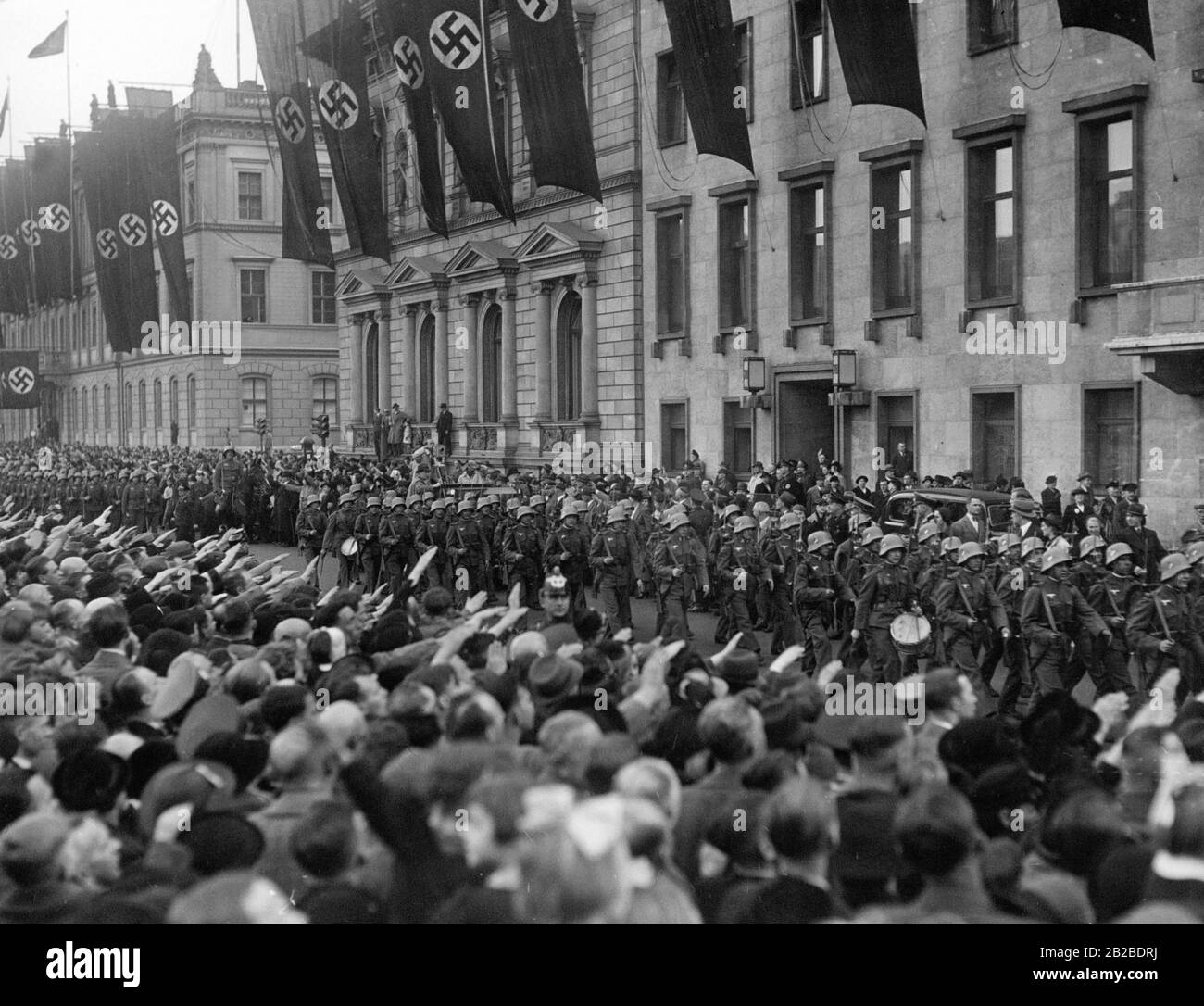 Das Wiener Infanterie-Bataillon wird in Berlin feierlich empfangen. Passanten durchmachen den Straßenrand und machen den Nazi-Salut. Hakenkreuzfahnen werden an den Gebäuden gehisst. Das Bataillon passiert die neue Reichskanzlei. Stockfoto