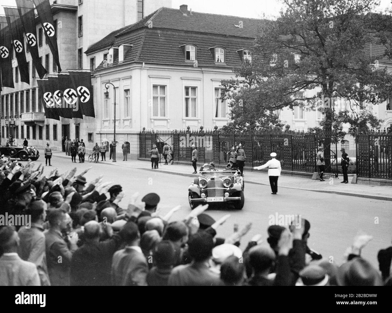 Der Stellvertreter von Adolf Hitler, Rudolf Heß, verlässt die Staatskanzlei, um zu den Olympischen Spielen im Reichsportfeld in Berlin zu gehen. Menschenmassen zeigen ihm den Nazi-Salut, als er die Staatskanzlei in seinem Auto verlässt. Stockfoto
