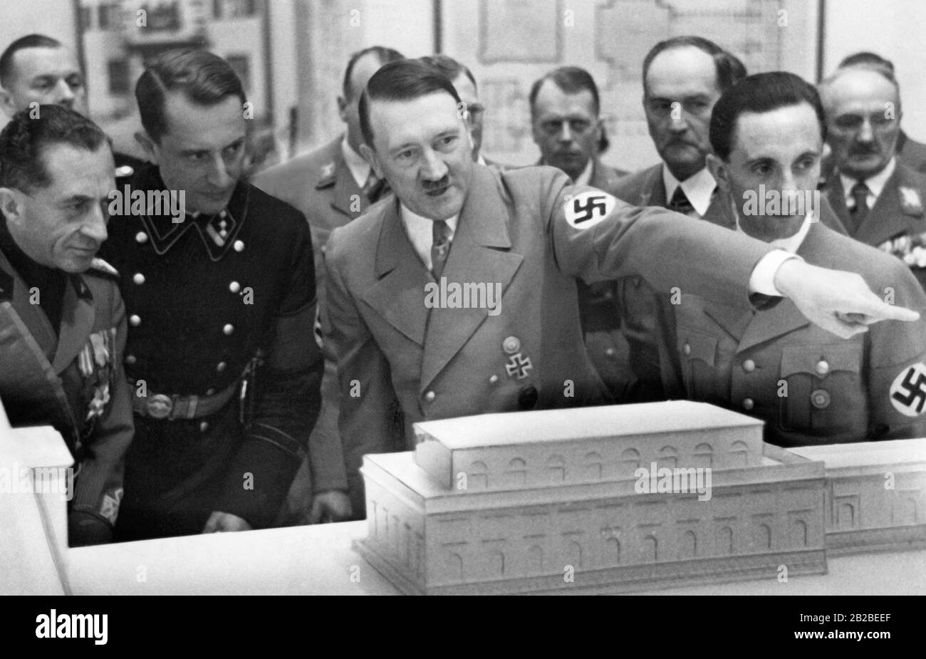 Adolf Hitler erklärt Joseph Goebbels (links) und einem italienischen Gast und einem SS-Offizier ein Modell von München. Stockfoto