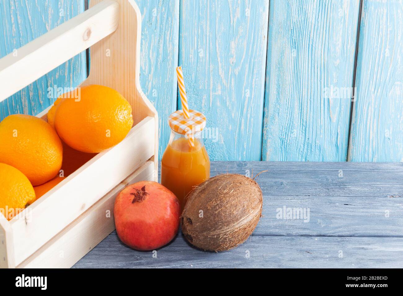 Viel Orangen im Karton und eine Flasche Saft, roter Granatapfel, Kokosnuss. Gesunde Ernährung. Stockfoto
