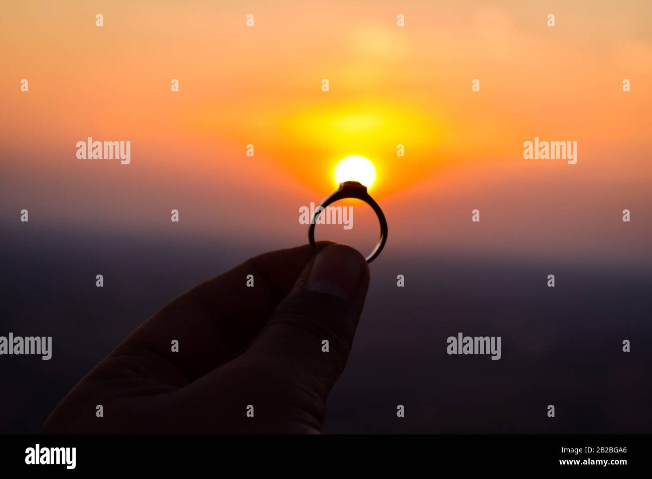 Ein schöner Ring in der Hand gehalten, um Sonne vorzuschlagen. Die Sonne wirkt wie der Diamant des Rings Stockfoto