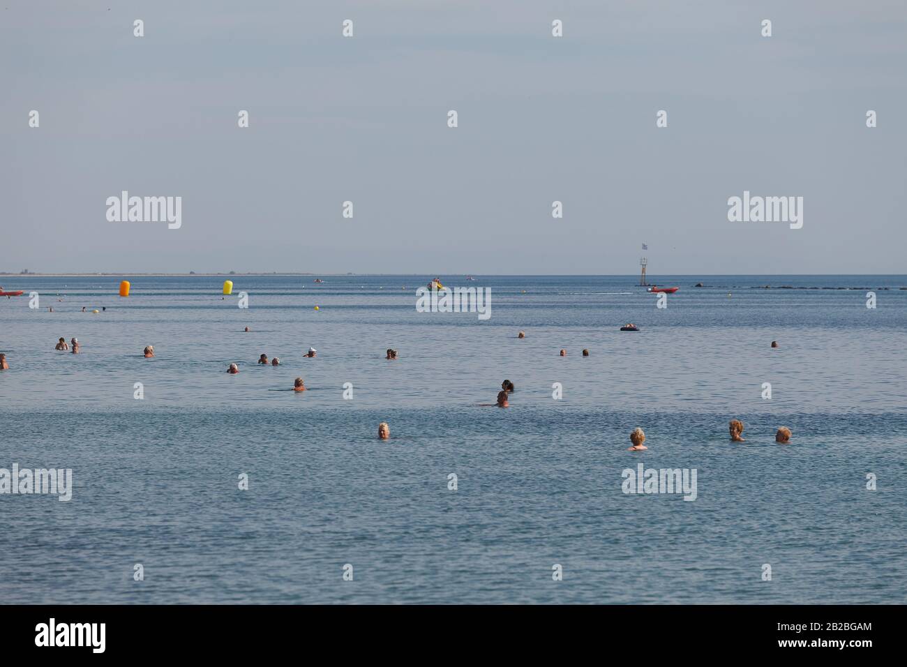 Paralia, GRIECHENLAND - 10. SEPTEMBER 2018: Strandszene. Menschen schwimmen und sonnen an der komfortablen Flachwasserküste voller Billighotels Stockfoto