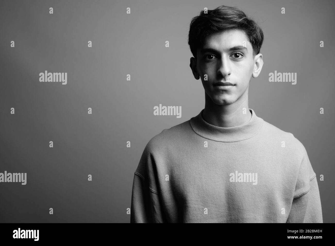 Jungen schönen persischen Teenager gegen grauer Hintergrund Stockfoto