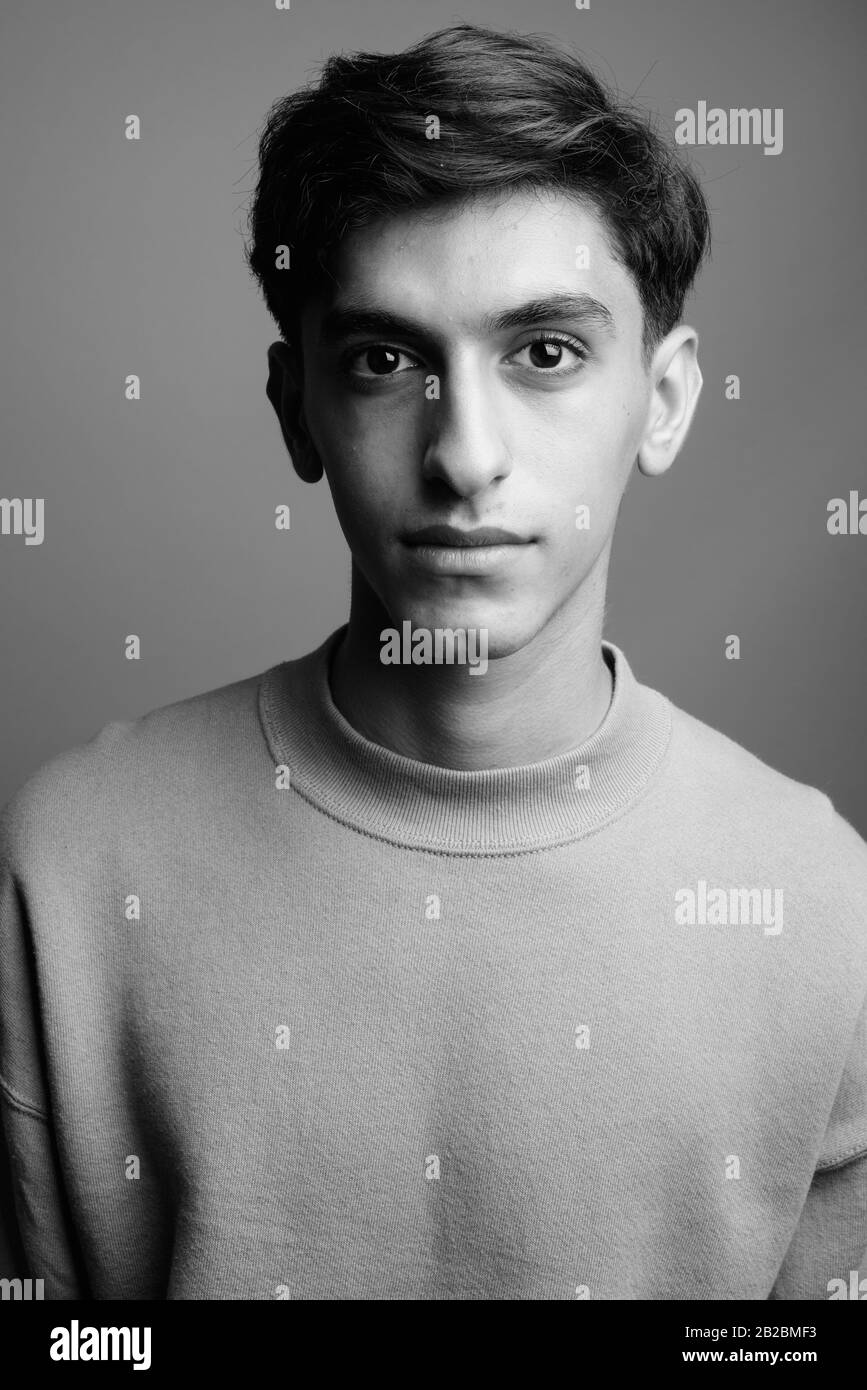 Jungen schönen persischen Teenager gegen grauer Hintergrund Stockfoto