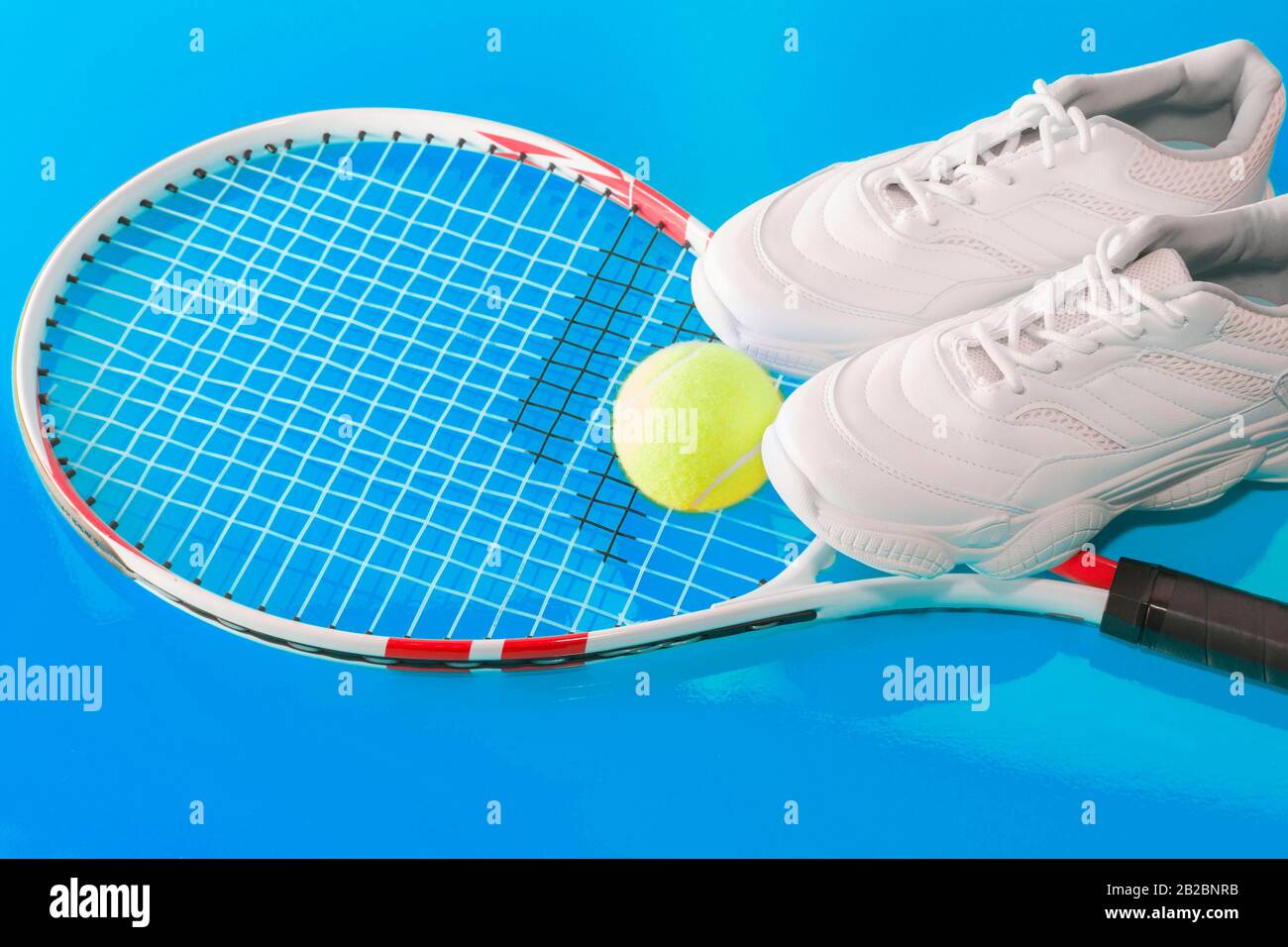 Tennisschläger mit Ball und Turnschuhen, auf hellem Hintergrund. Fotografiert im Studio Stockfoto