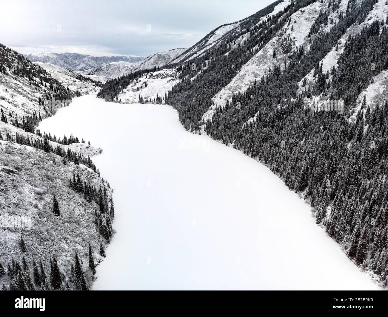 Luftaufnahme von Kolsa-Bergsee und Wald zur Winterzeit in den Bergen Kasachstans. Drohnenschuss, Draufsicht. Stockfoto