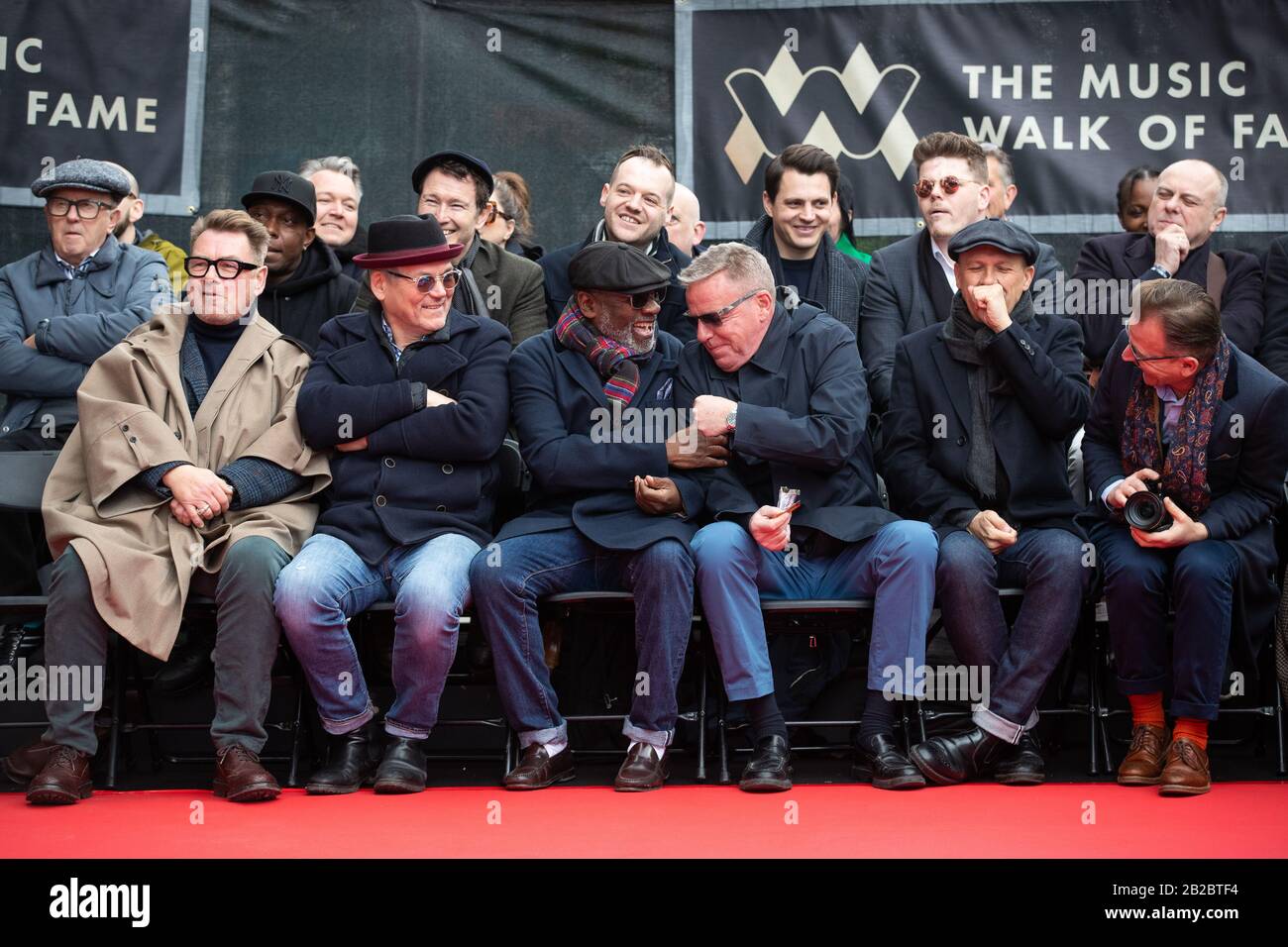 (Von links nach rechts in der ersten Reihe) Chas Smash, Mike Barson, Lynval Golding, Graham McPherson alias Suggs, Mark Bedford und Dan Woodgate während der Enthüllung eines Steins zur Ehrung der Band Madness auf dem Music Walk of Fame in Camden, London. Stockfoto