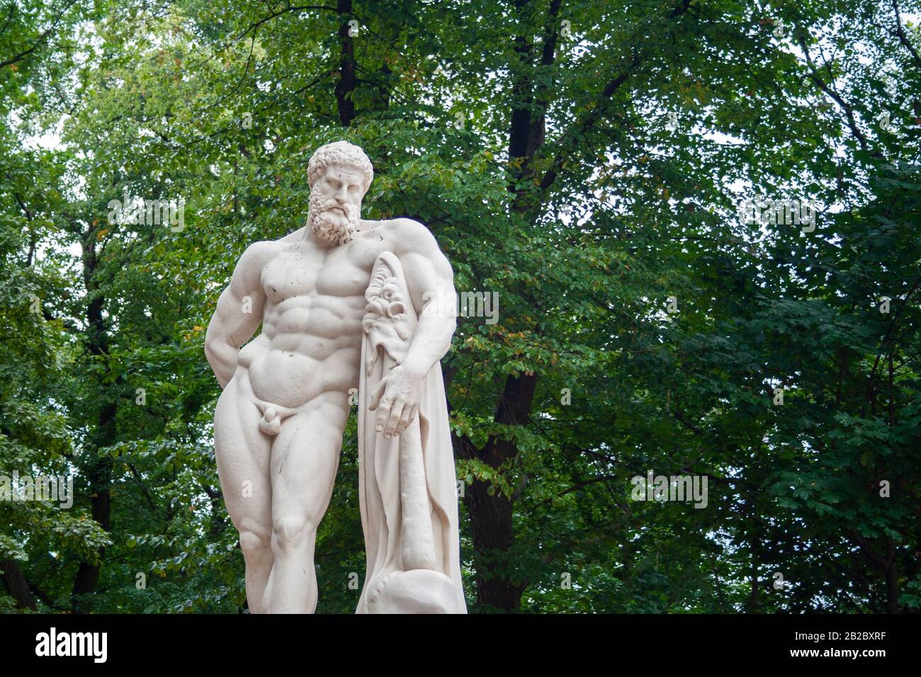 Skulptur der nackten muskulösen Heracle im Park mit Club. Skulptur von bärtigen Mann nackt Stockfoto