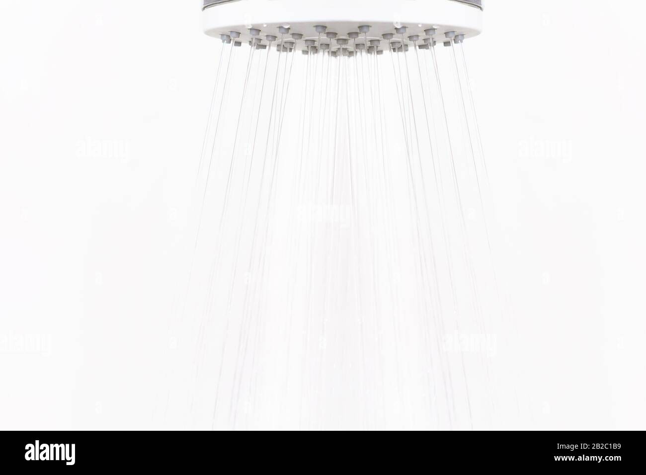 Wasserstrahl vom Duschkopf auf hellem Hintergrund. Hintergrund des wassersparenden Konzepts. Stockfoto