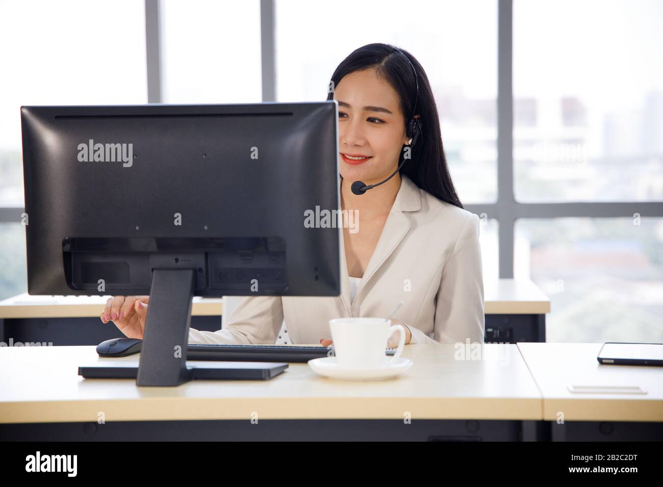 Die asiatische Callcenter-Betreiberin konzentriert sich auf ihre Arbeit im Personal Computer. Konzept für Kundenservice, Lifestyle im Büro, Mitarbeiter. Stockfoto
