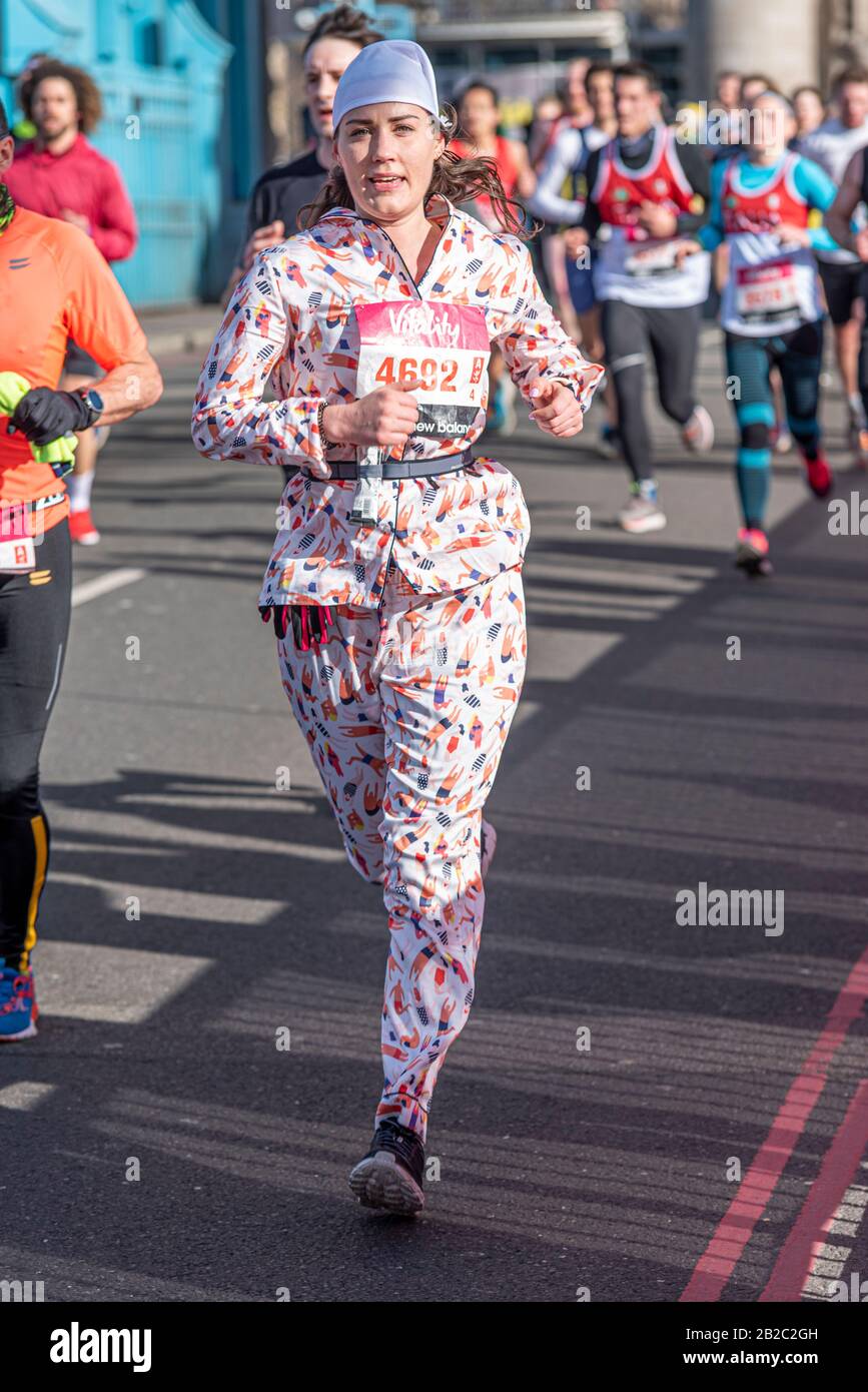 Jennifer Graham, Rennfahrerin im Vitality Big Half Marathon Crossing Tower Bridge, London, Großbritannien. Weibliche lustige Läuferin im Schlafanzug Stockfoto