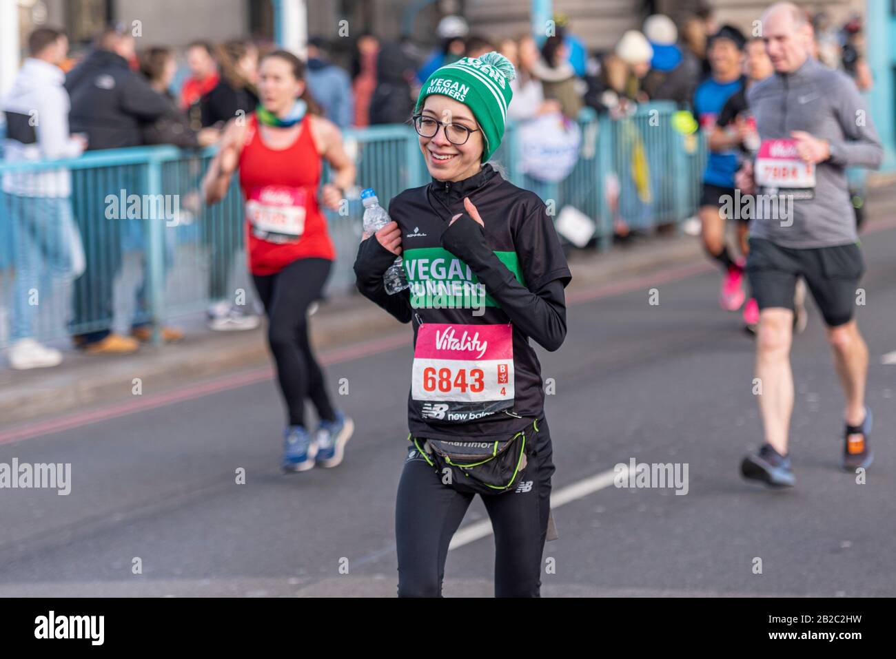 Bethany Ashman von Vegan Runners UK Racing in The Vitality Big Half Marathon Crossing Tower Bridge, London, Großbritannien. Dünne, dünne weibliche Läuferin Stockfoto
