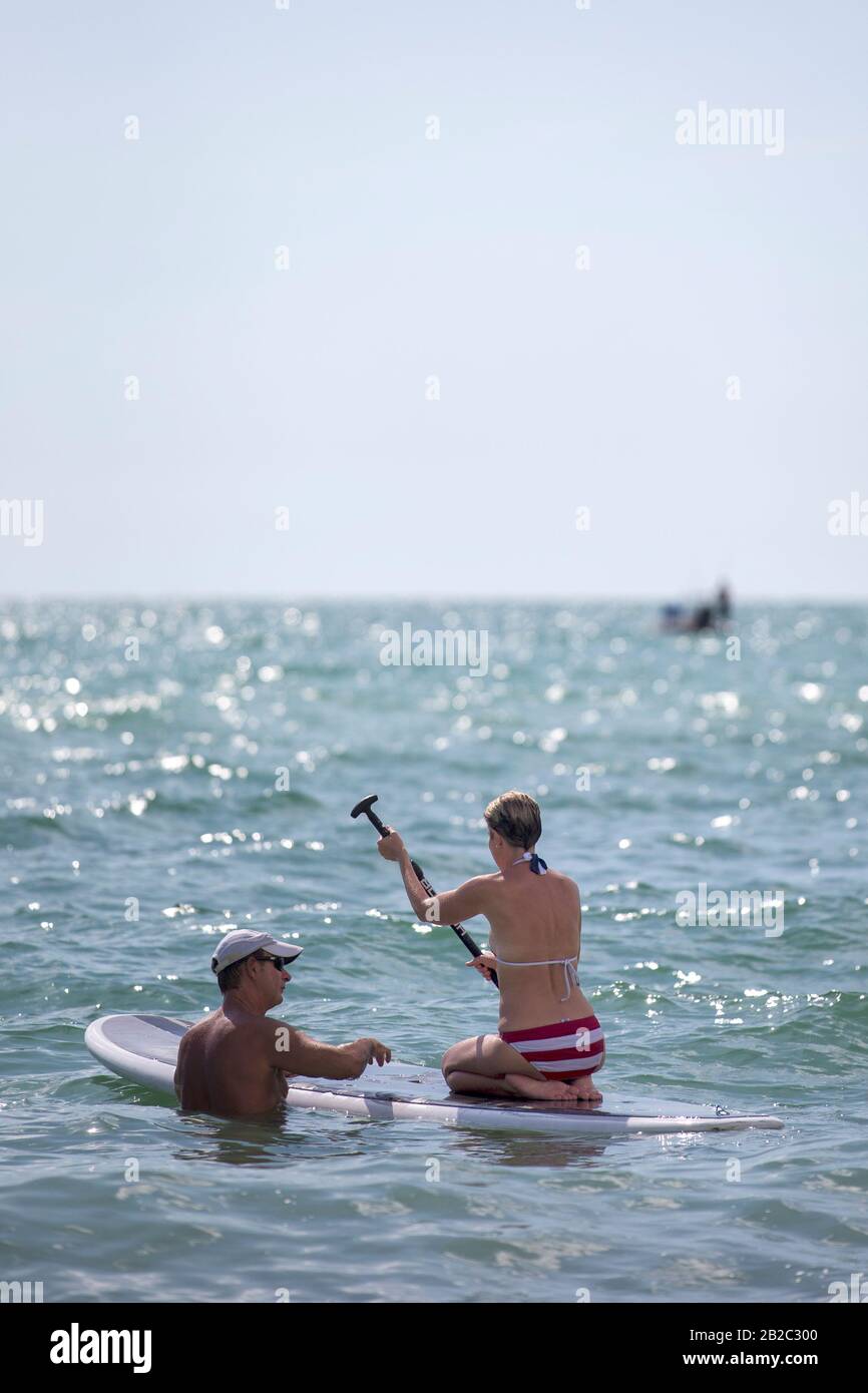 Ein Paar im Wasser in Florida, lernen, wie man ein SUP Stand Up Paddle Board verwendet. Für Wassersportaktivitäten. Stockfoto