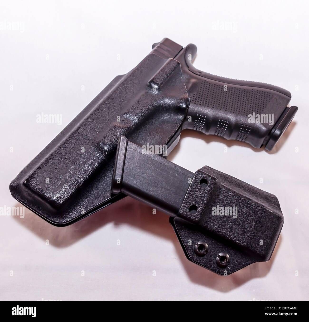 Eine schwarze Pistole in einem Kunststoffholster mit einem geladenen Magazinholster auf weißem Hintergrund Stockfoto