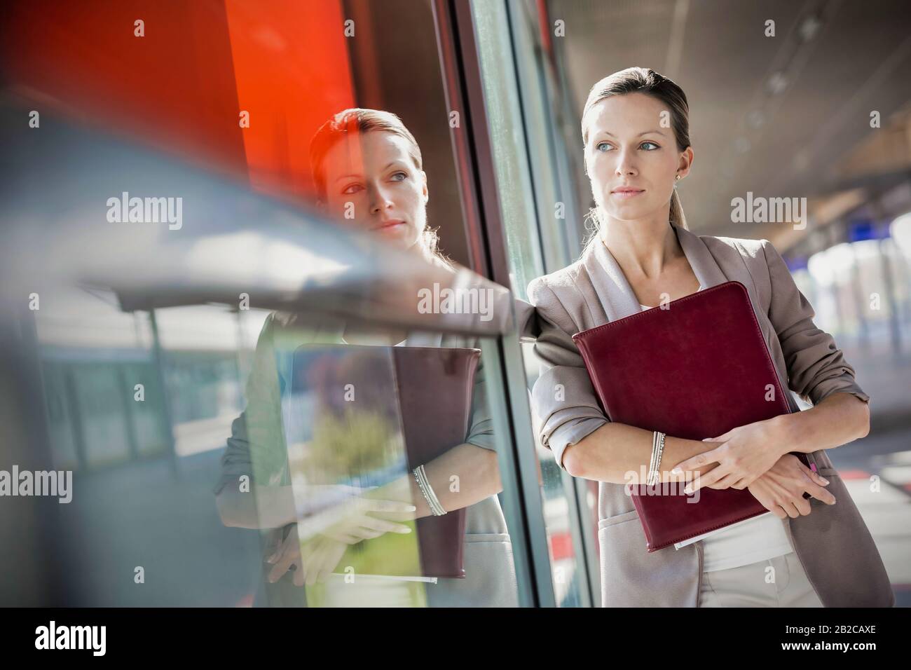 Junge, attraktive Geschäftsfrau, die während des Durchblickes ein Dokument hält und hält Stockfoto