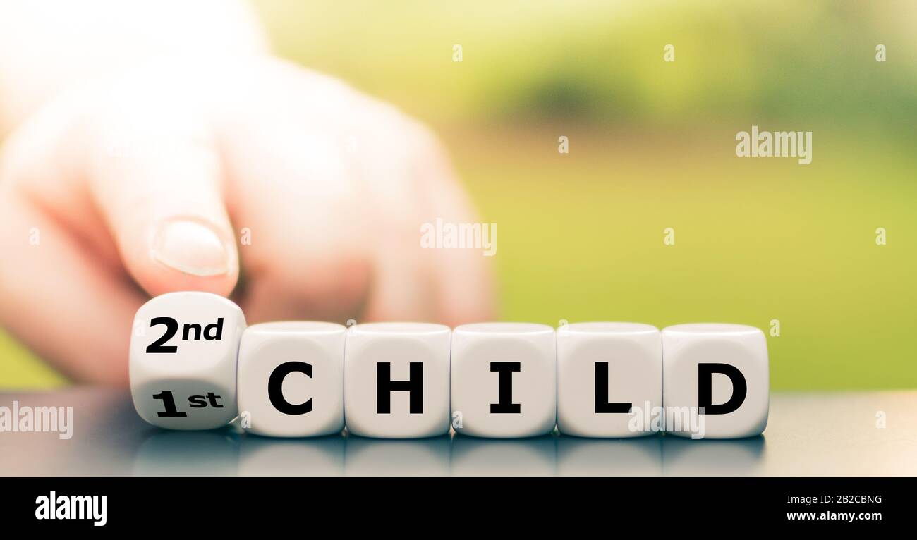 Ein zweites Kind wird erwartet. Hand dreht Würfel und ändert den Ausdruck "1. Kind" in "2. Kind". Stockfoto